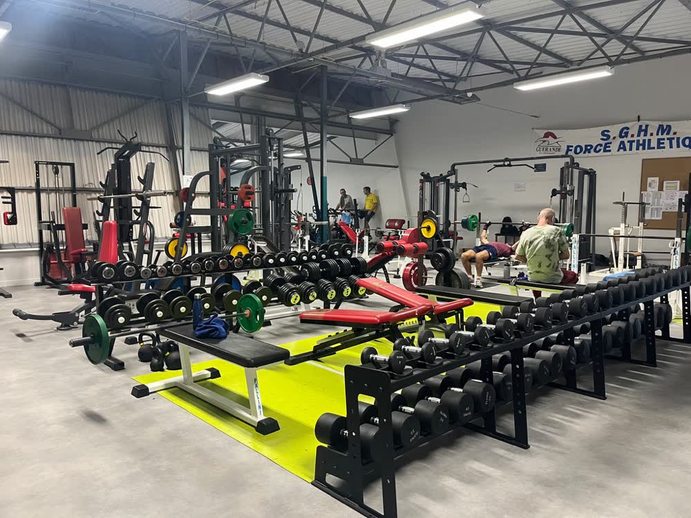 Rangée d'haltères sous la banderole SGHM Force Athlétique, salle des sports Jean Ménager